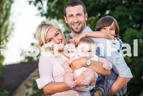 Happy Family Posing Outdoors In Front Of House